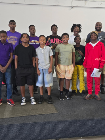 Getro Elize in group photo with grade level children and staff from Omega Manhood Bootcamp