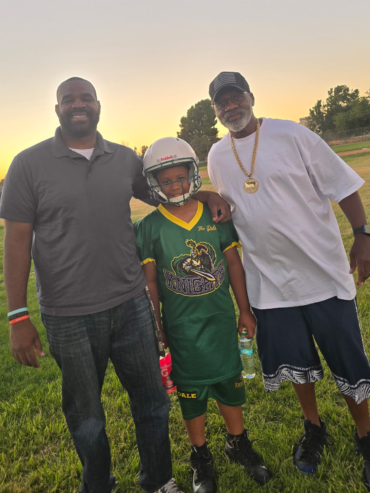 Getro Elize posing together with child wearing football gear and another person