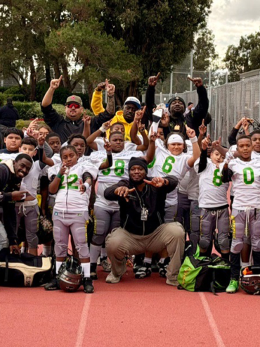 Getro Elize posing with group of grade level children in football team cheering