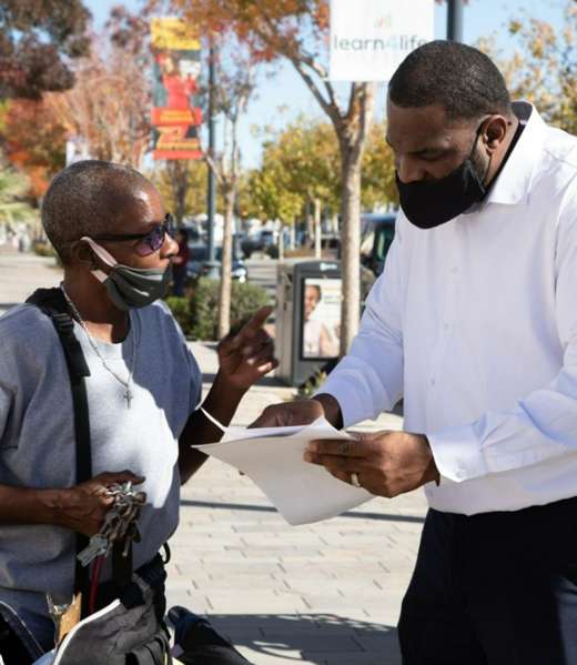 Getro Elize reviews paperwork with a resident outdoors.
