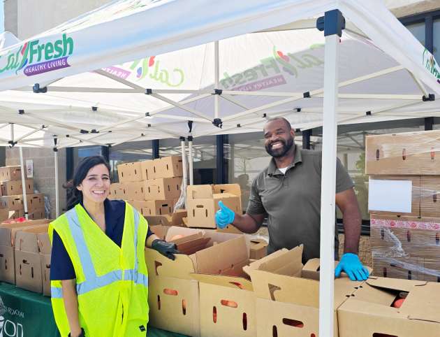 Getro Elize with smiling with thumbs up staff at food distribution center